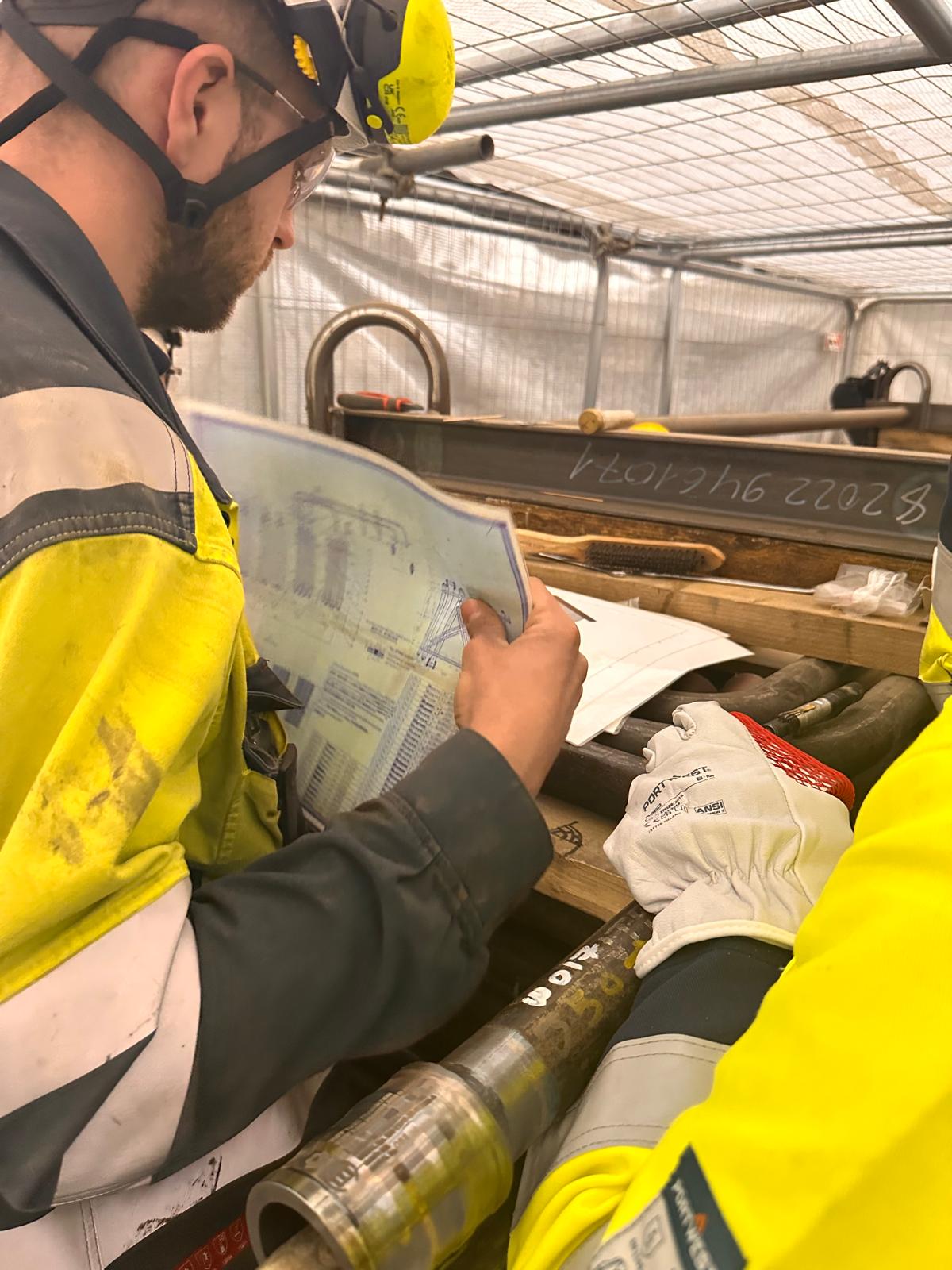 Site personnel reviewing installation drawings alongside prepared tube assemblies at Bouchain